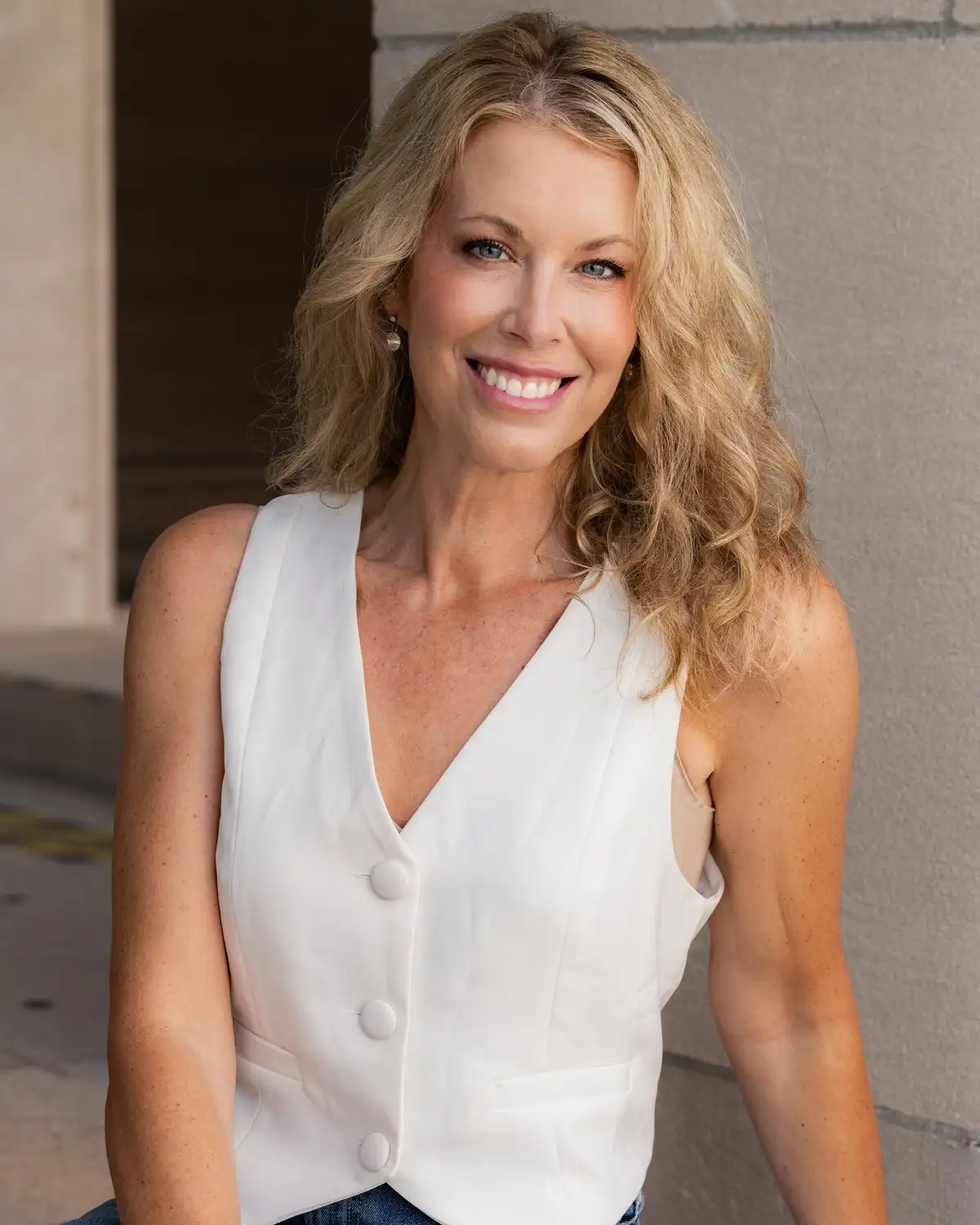 Cara, co founder and managing broker of Alpine Property Management, smiling on a stone ledge