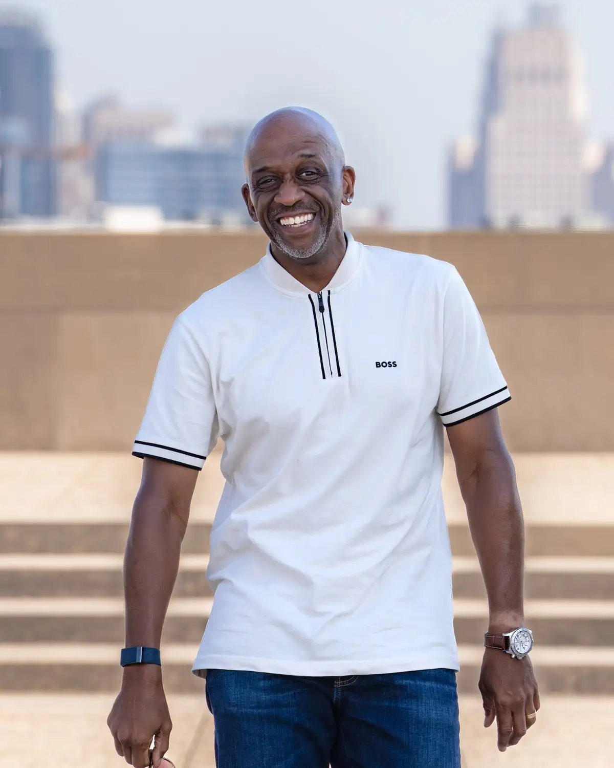 Derrick, construction manager at Alpine, smiling on a plaza with the Kansas City skyline behind him