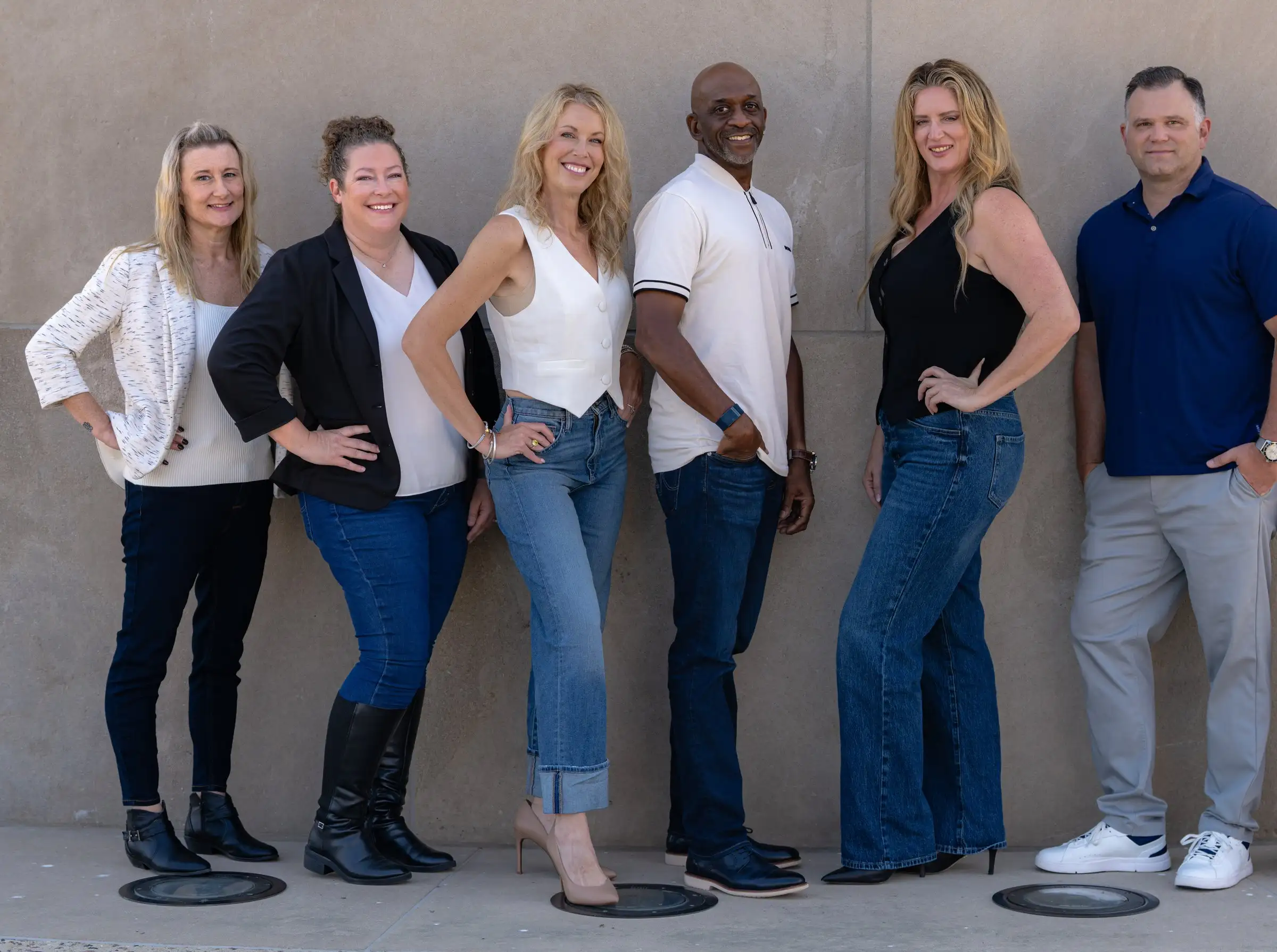 The Alpine Property Management team standing together against a stone wall in Kansas City